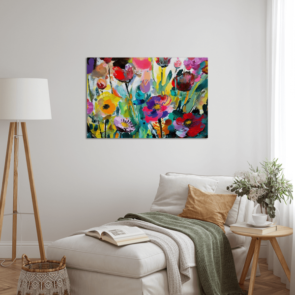 A bright painting depicting flowers hung up on a wall above a couch.